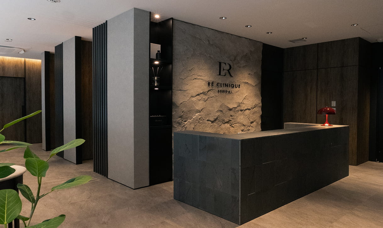 高級感のある内装の受付カウンターで、「RE CLINIQUE SENDAI」のロゴが壁に表示されている